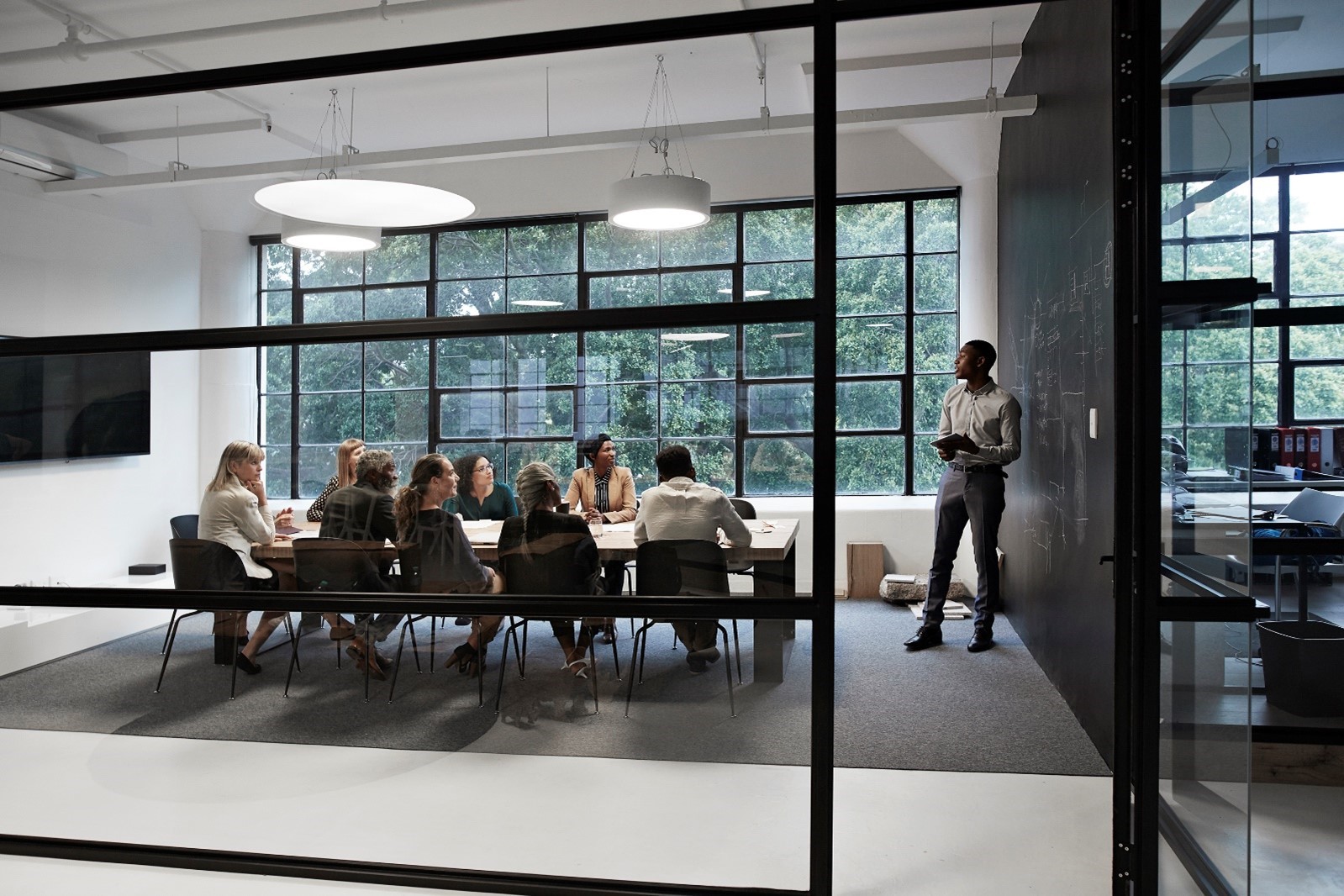 Image capturing a seminar in a boardroom, where a presenter discusses leadership coaching concepts with an engaged group of leaders 