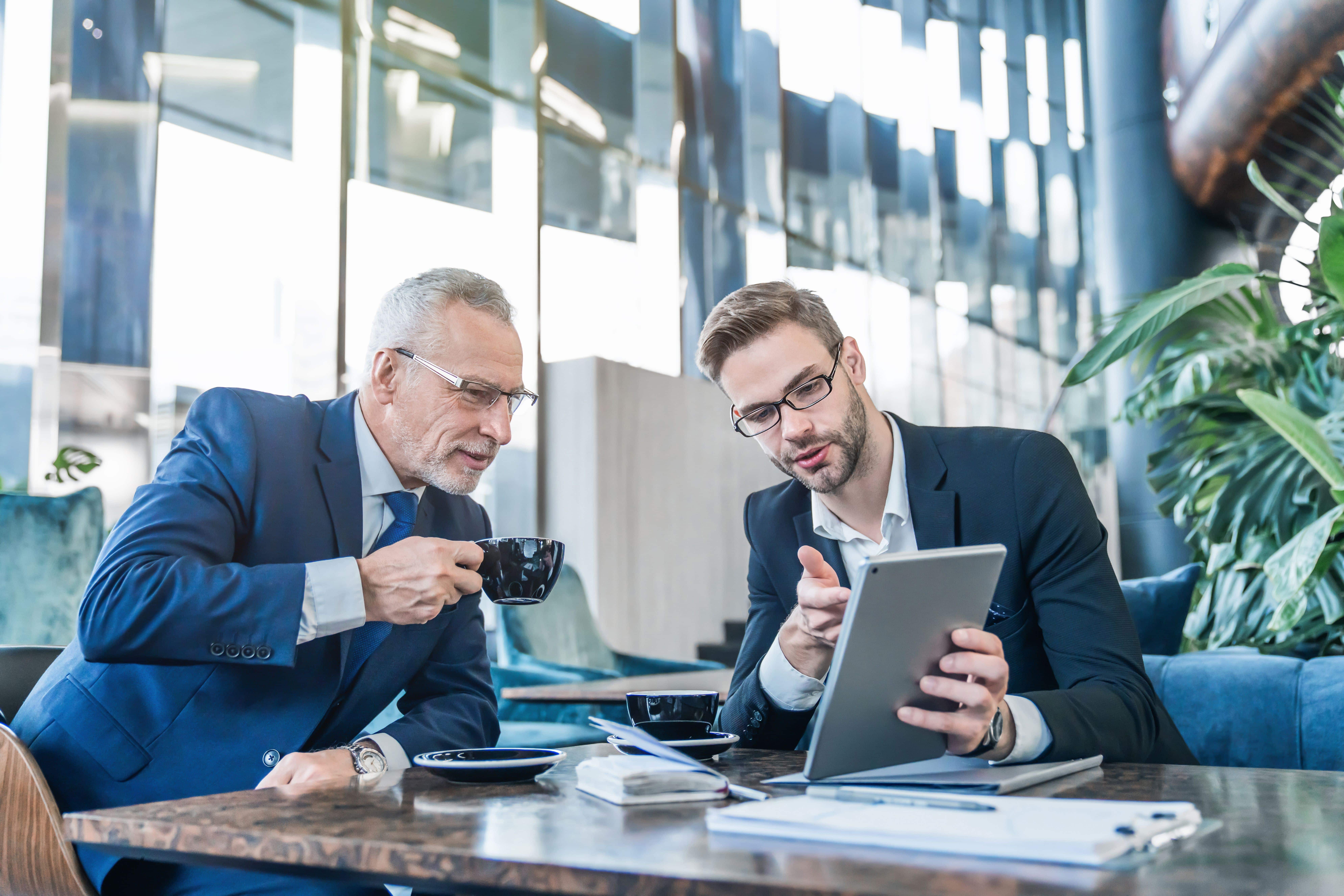 Image of a senior executive and an executive coach engaged in data analysis on a laptop, reviewing the strategic approach to leadership development