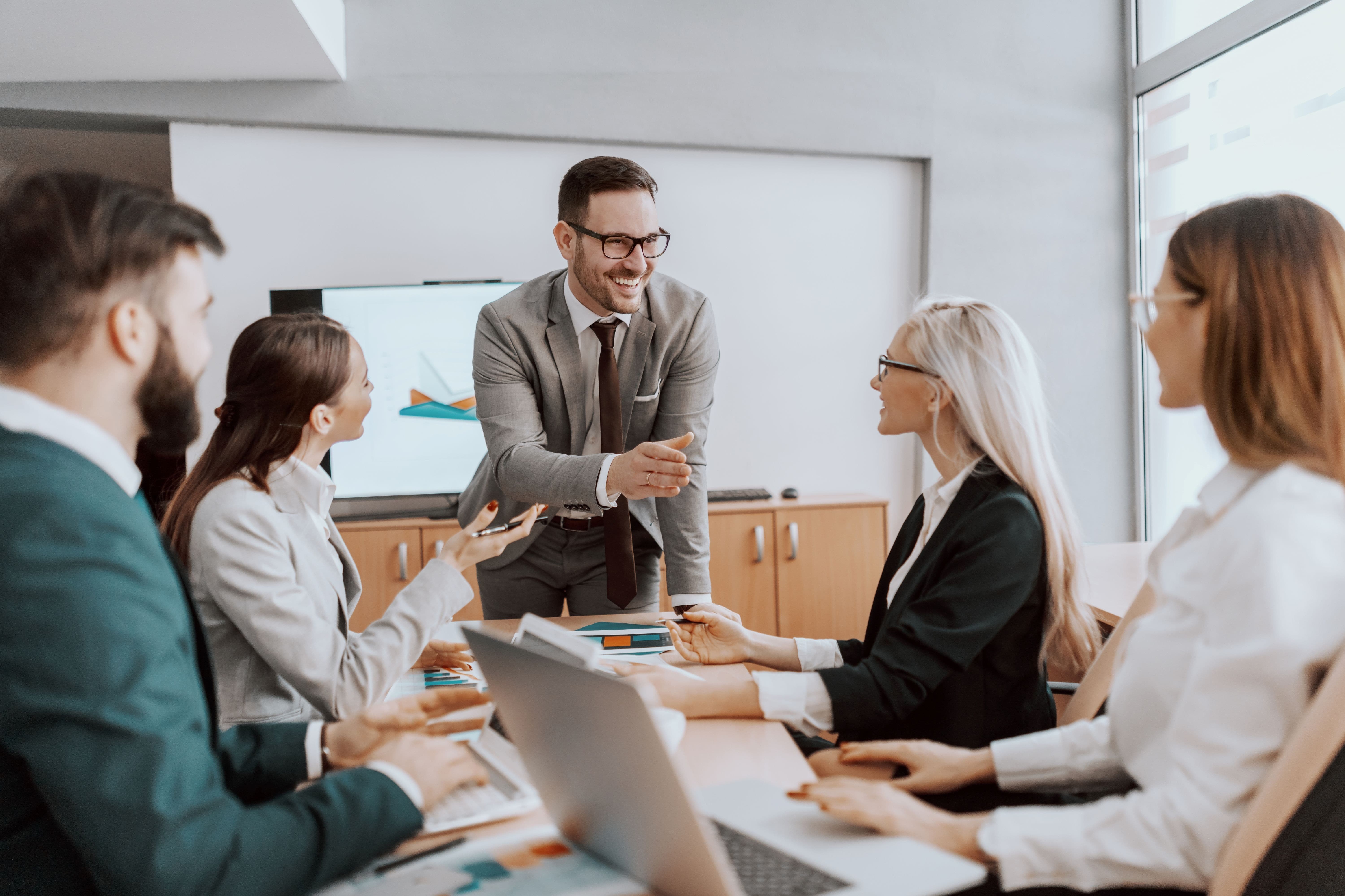 Image of a dynamic team coaching session, where a male team coach engages with a diverse group of four leaders, fostering teamwork and leadership enhancement
